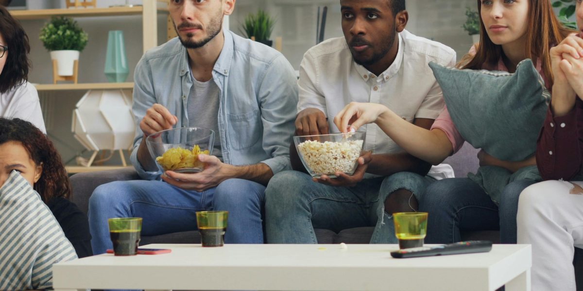 Friends sharing a lighthearted moment, laughing together while watching an entertaining action-comedy film.
